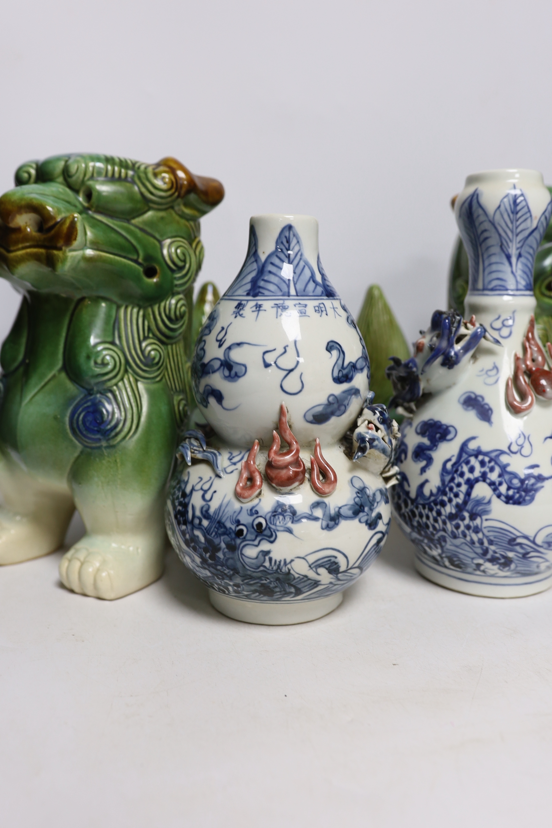 Two Chinese blue and white with iron red ‘dragon’ vases and a near pair of lion dogs, tallest 26cm